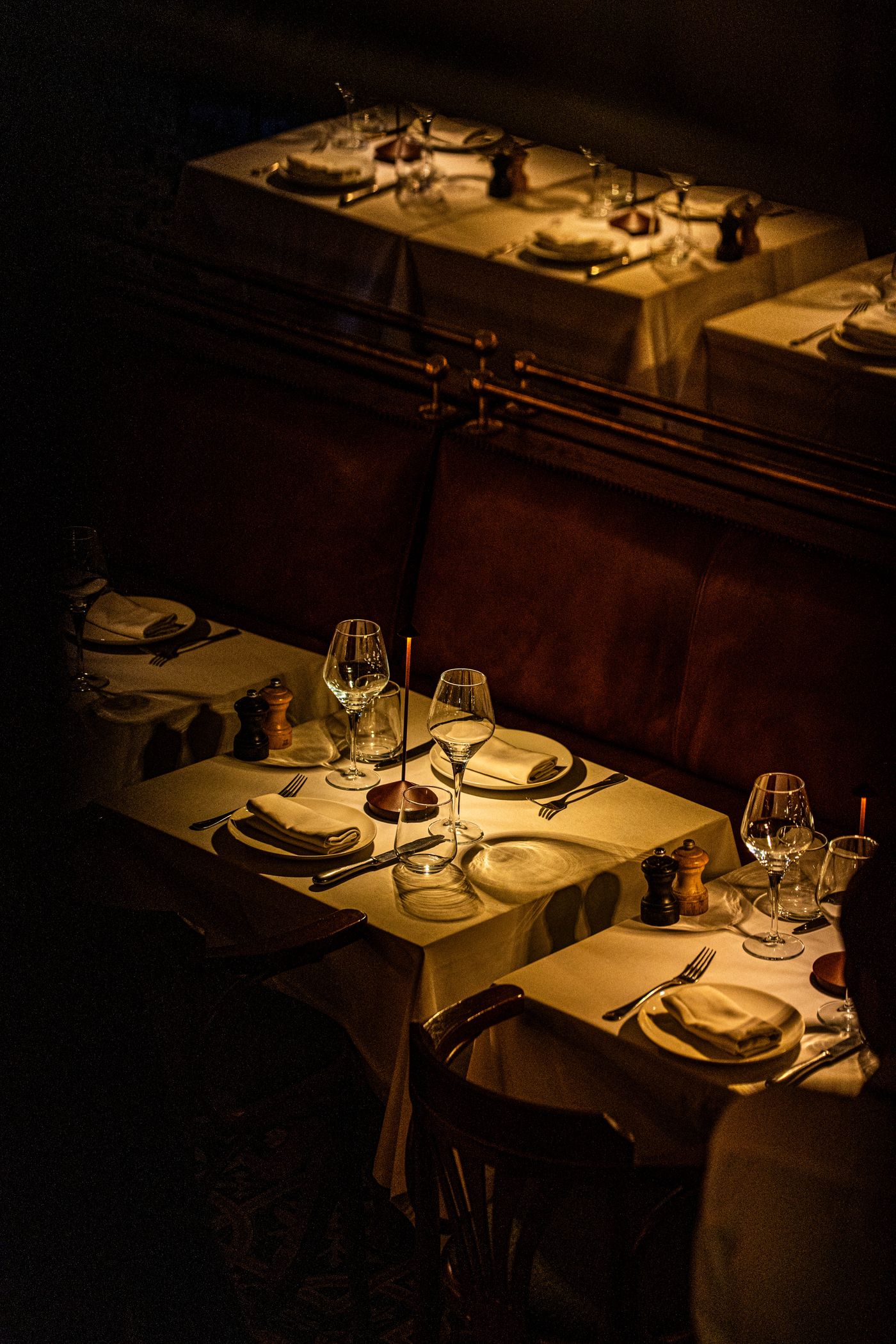 Warm, dim-lit dining room with candlelight and oxblood banquette seating